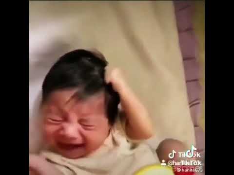 Newborn baby pulling his own hair and crying.